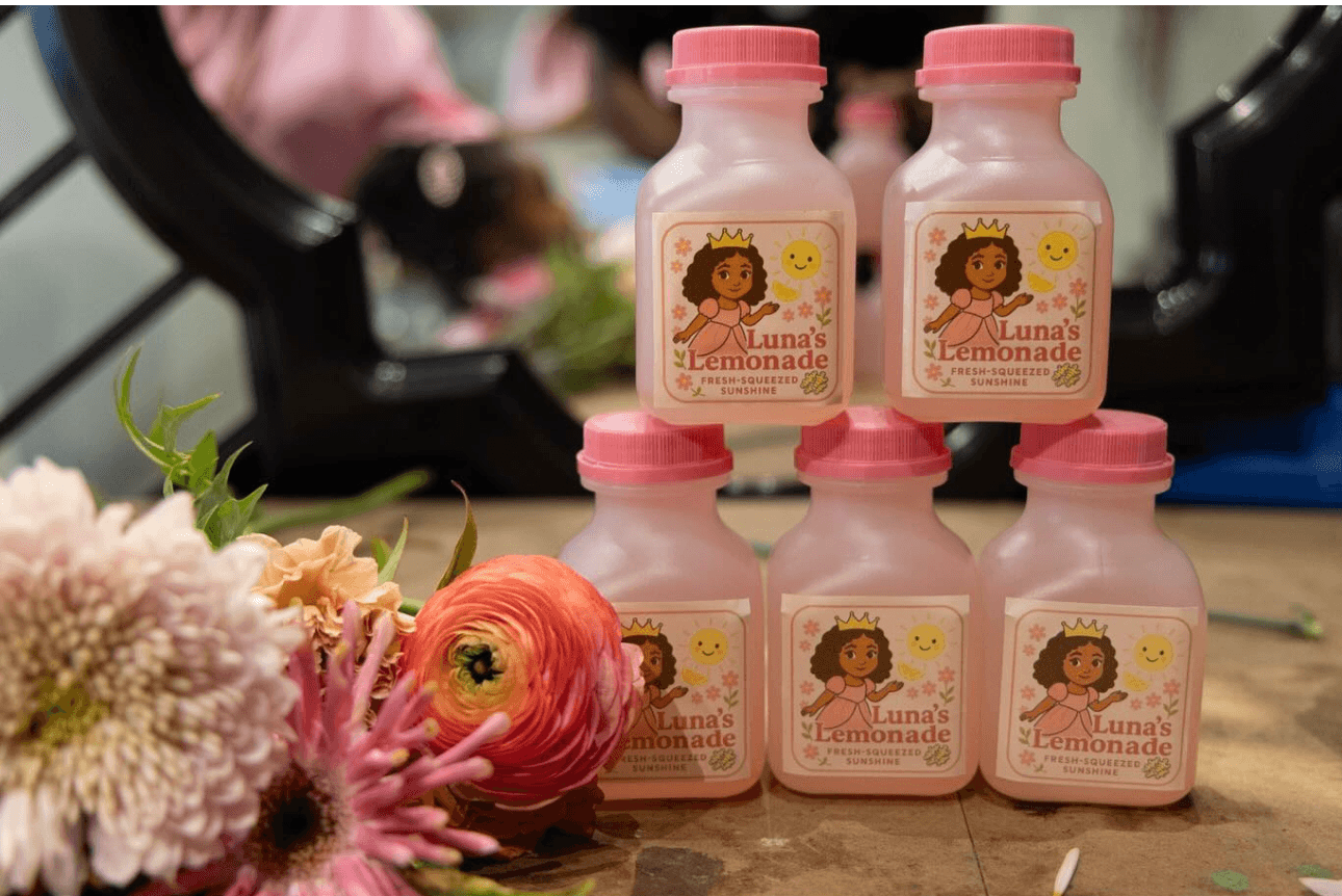 Pink Luna's Lemonade bottles arranged on a table beside fresh flowers